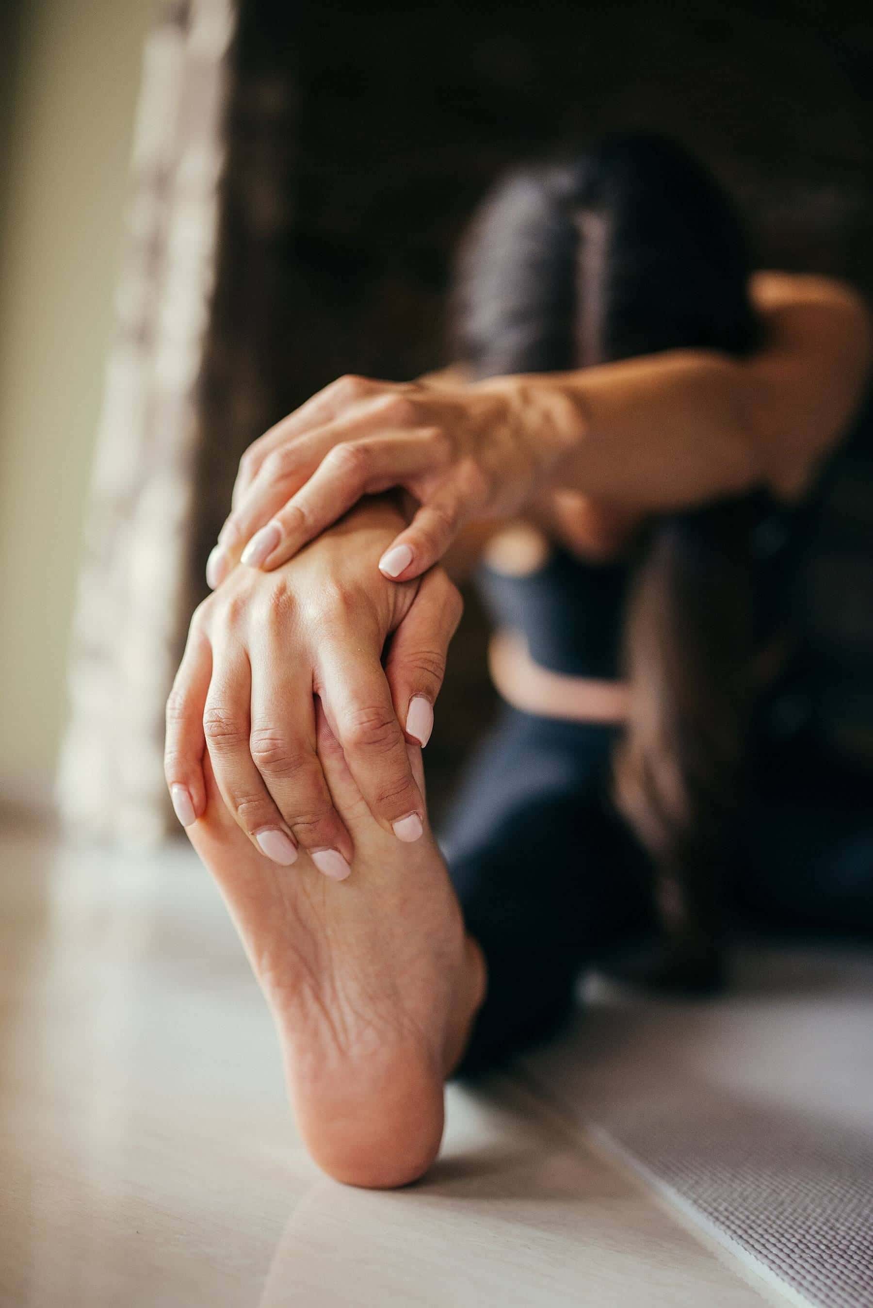 Close-up of a woman's hand gripping her foot during a seated hamstring stretch