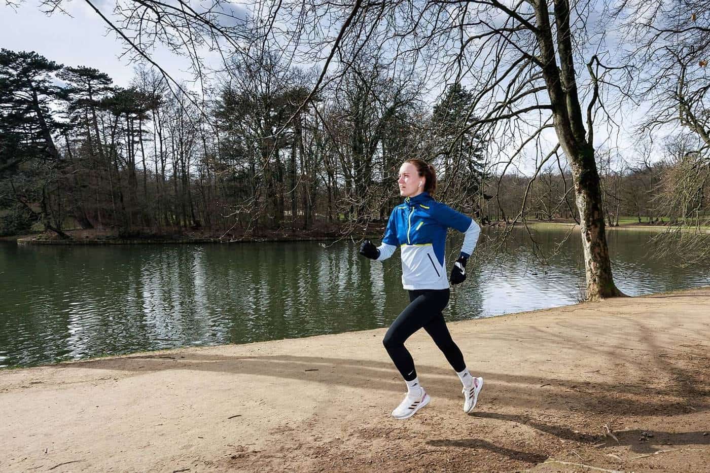 A woman running along a lakeside path in a park